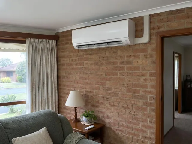 White split system on a brick interior wall above a lounge room in Ingle Farm