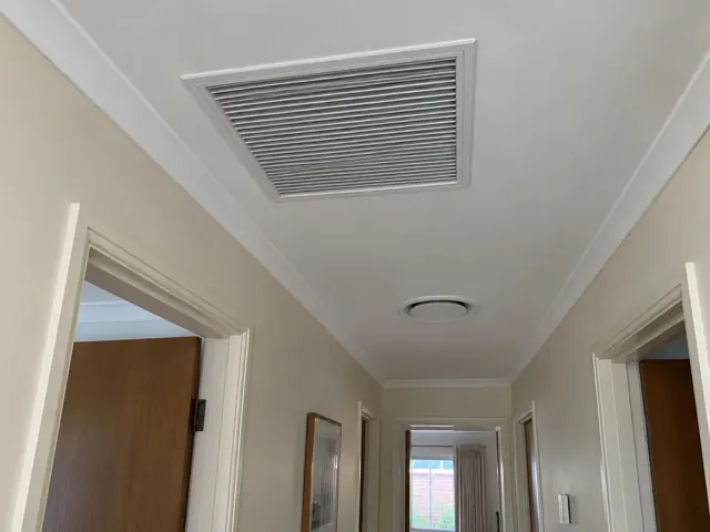 Ceiling return-air grille in a hallway with white walls and doorways in Klemzig